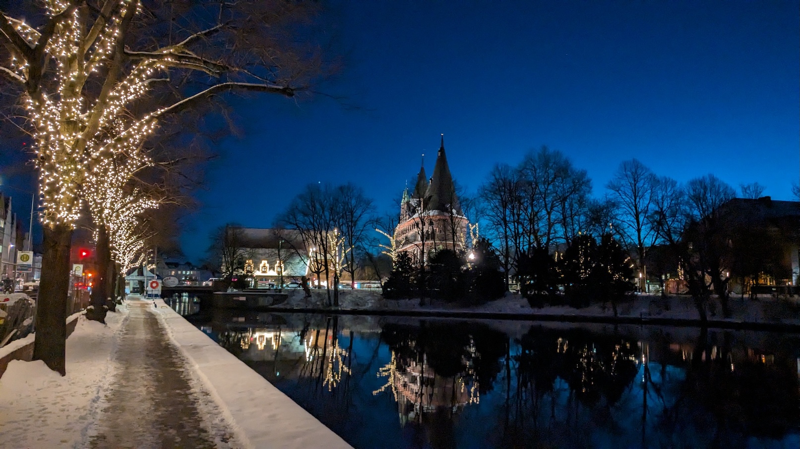 Ein historisches Stadttor an einem Fluss zur blauen Stunde. Es liegt etwas Schnee.